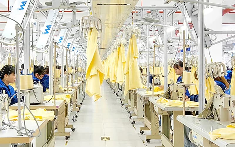 Overhead hanger production system carrying yellow garment panels between sewing stations